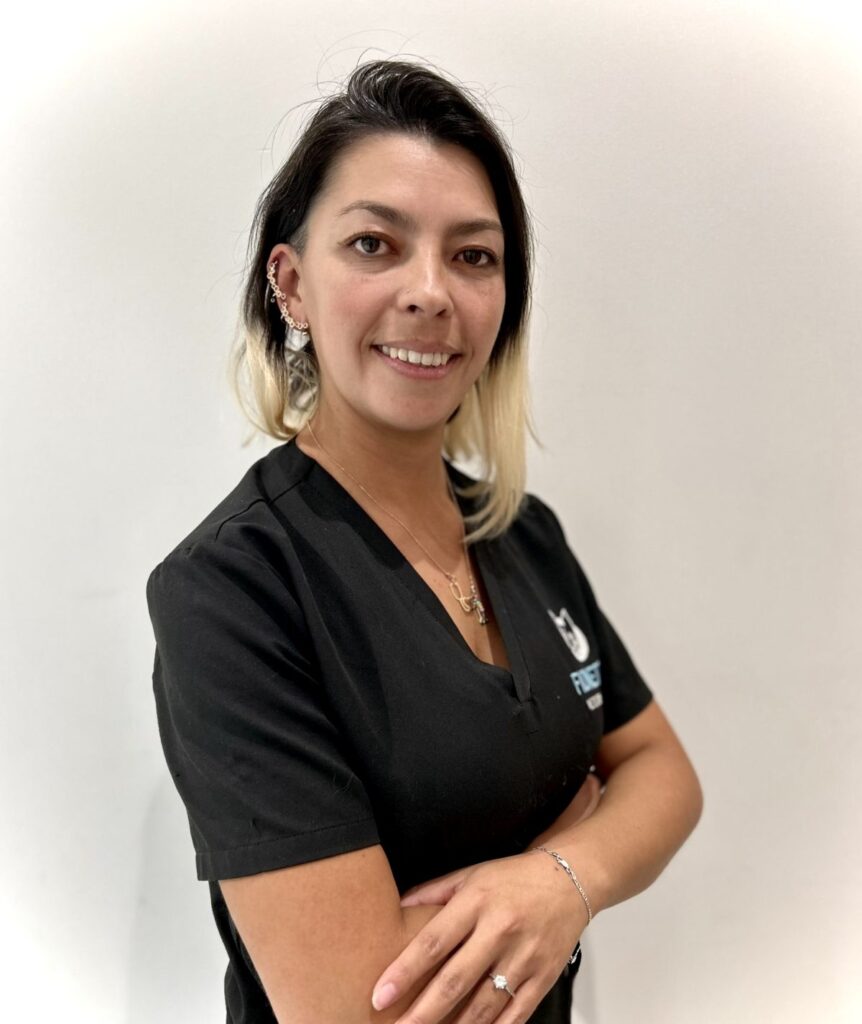 Persona sonriendo con uniforme negro, fondo blanco.
